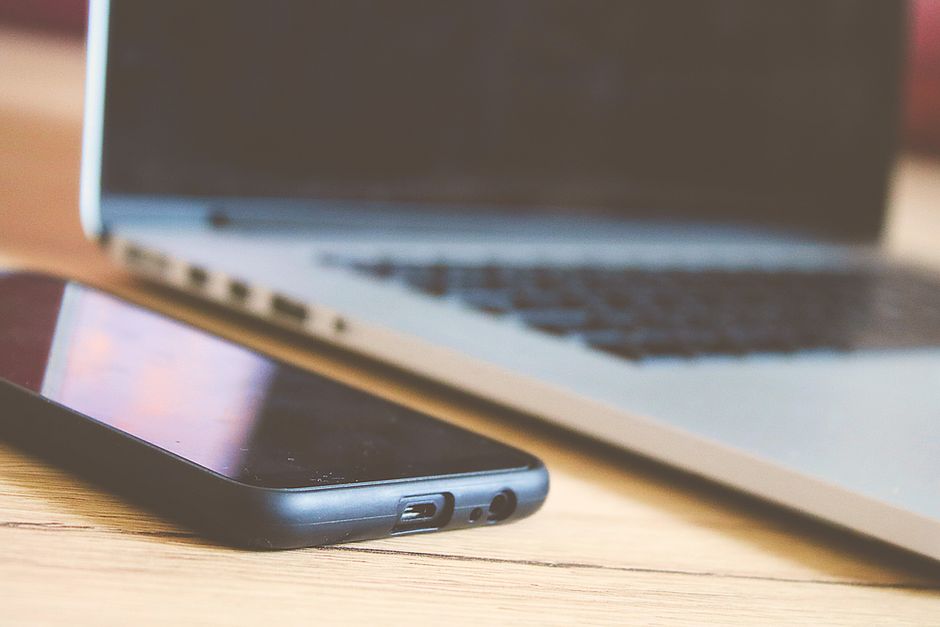 Close-up view of a smartphone and laptop on a wooden desk, perfect for illustrating modern technology.